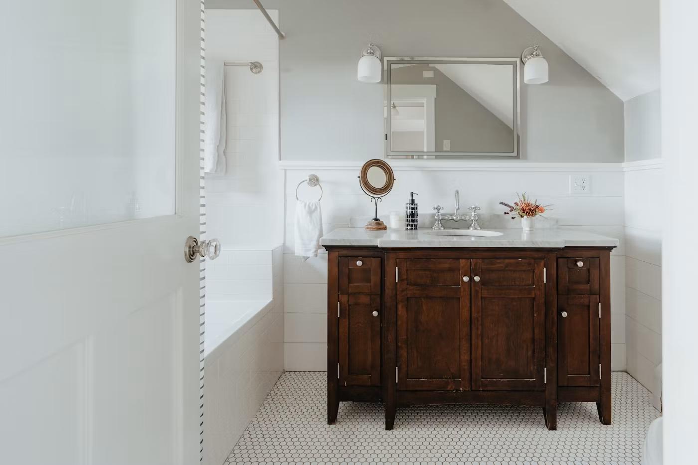 Traditional white bathroom with wood vanity and hex tile floor